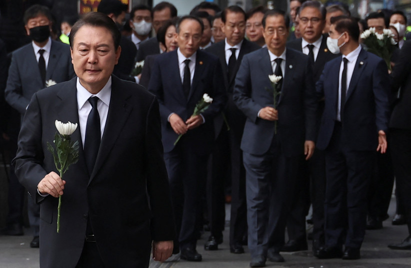  South Korean President Yoon Suk-yeol holds a flower to be placed as a tribute to victims as he visits the scene of a crowd crush that happened during Halloween festivities, in Seoul, South Korea, November 1, 2022.  (credit: KIM HONG-JI/ REUTERS)
