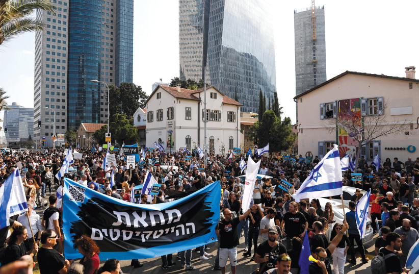  Israelis working in the hi-tech sector hold aloft the Israeli flag and a banner with the Hebrew words ‘The hi-tech protest’ as they demonstrate against proposed judicial reforms on January 24.  (credit: CORINNA KERN/REUTERS)