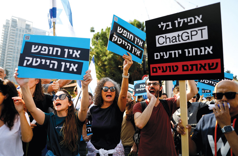  Protesters hold signs with the Hebrew words ‘No democracy, no hi-tech’ and ‘Even without ChatGPT we know that you’re wrong’ as they demonstrate in Tel Aviv on January 24.  (credit: CORINNA KERN/REUTERS)