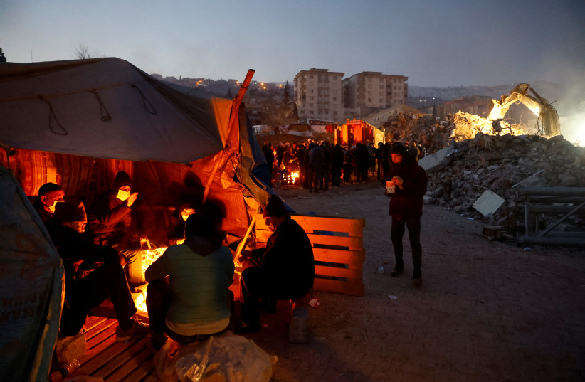  People sit around a fire near the site of a collapsed building, as the search for survivors continues, in the aftermath of an earthquake, in Kahramanmaras, Turkey February 9, 2023. (credit: SUHAIB SALEM/REUTERS)