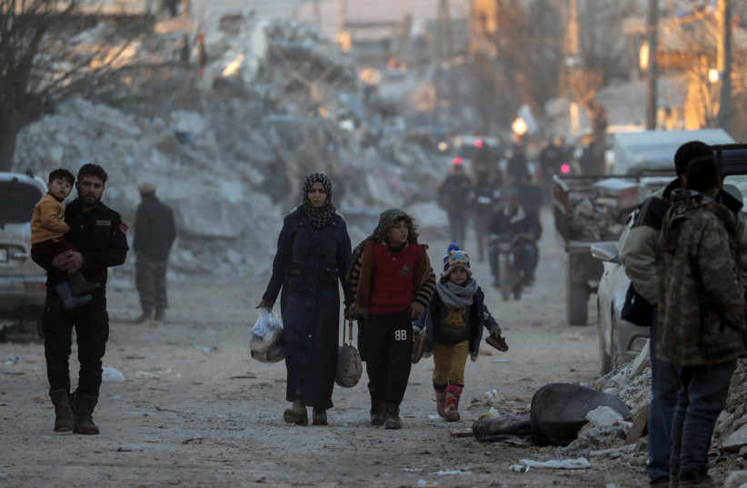 Des gens passent devant des bâtiments endommagés, à la suite d'un tremblement de terre, dans la ville rebelle de Jandaris (crédit photo : REUTERS)