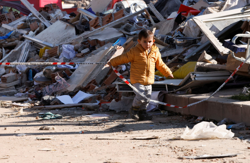  A child walks on the street surrounded by rubble following the earthquake in Hatay, Turkey (photo credit: REUTERS)