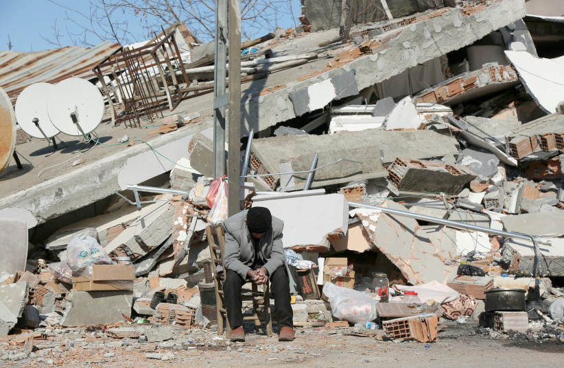  Seho Uyan, who survived a deadly earthquake, but lost his four relatives, sits in front of a collapsed building in Adiyaman, Turkey February 11, 2023. (photo credit: REUTERS)