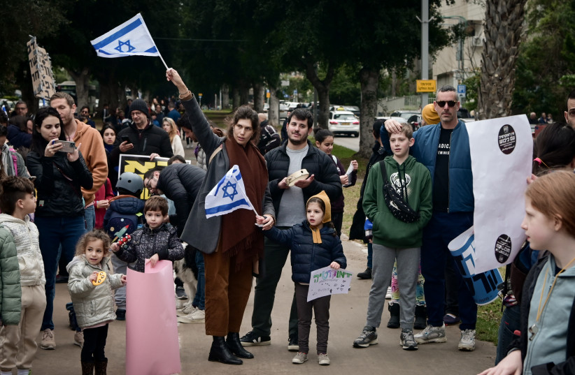  Israeli parents and children hold signs and wave the Israeli flag as they protest the Israeli government's planned legal reforms. February 13, 2023. (credit: AVSHALOM SASSONI/FLASH90)