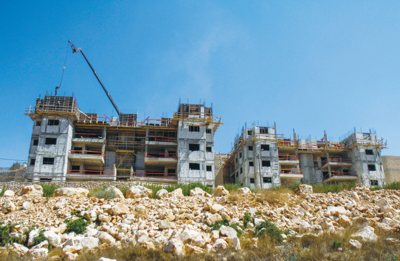  CONSTRUCTION WORK takes place on new housing in Kiryat Netafim, in Samaria, south of Nablus, last summer. (credit: NASSER ISHTAYEH/FLASH90)