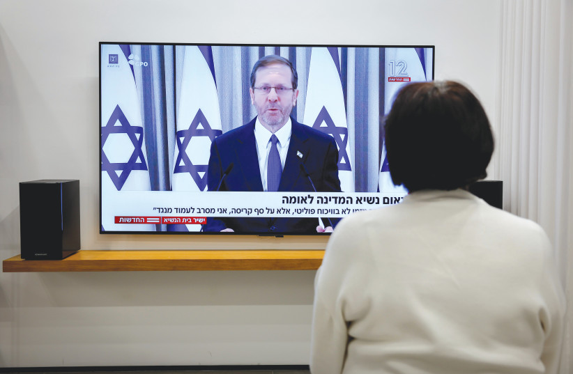  A WOMAN IN Kibbutz Mishmar David watches President Issac Herzog’s speech on the proposed changes to the legal system, on Sunday night.  (photo credit: NATI SHOHAT/FLASH90)