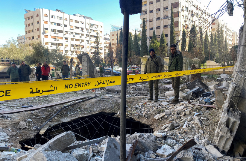  Police officers stand on the rubble of a damaged building at the site of a rocket attack, in central Damascus' Kafr Sousa neighborhood, Syria, February 19, 2023.  (credit: FIRAS MAKDESI/REUTERS)