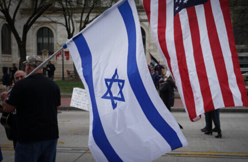  A man walking with an Israeli and an American flag (credit: Religion Unplugged)