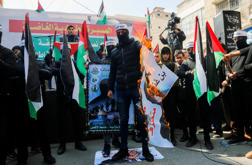  A Palestinian masked activist steps on a picture of Israeli National Security Minister Itamar Ben-Gvir, as he burns another one, during a protest to condemn an Aqaba meeting between Israeli and Palestinian officials, in Gaza City, February 26, 2023.  (photo credit: Reuters/Arafat Barbakh)