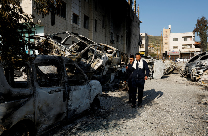  Palestinians walk near cars burned in an attack by Israeli settlers following an incident where a Palestinian gunman killed two Israeli settlers near Huwara in the West Bank, February 27, 2023. (credit: AMMAR AWAD/REUTERS)