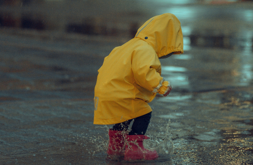 A child plays outdoors in the rain (illustrative) (photo credit: PEXELS)