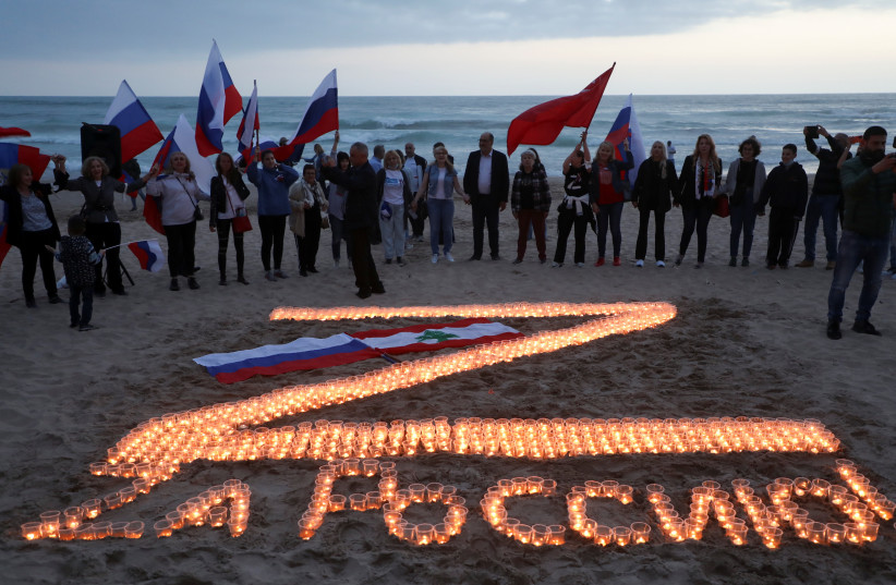  Lebanese and Russians living in Lebanon carry flags as they stand near lit candles reading, ''For Russia!'' during a rally in support of Russia, amid Russia's invasion of Ukraine, at a beach in Beirut, Lebanon April 9, 2022. (credit: REUTERS/MOHAMED AZAKIR)