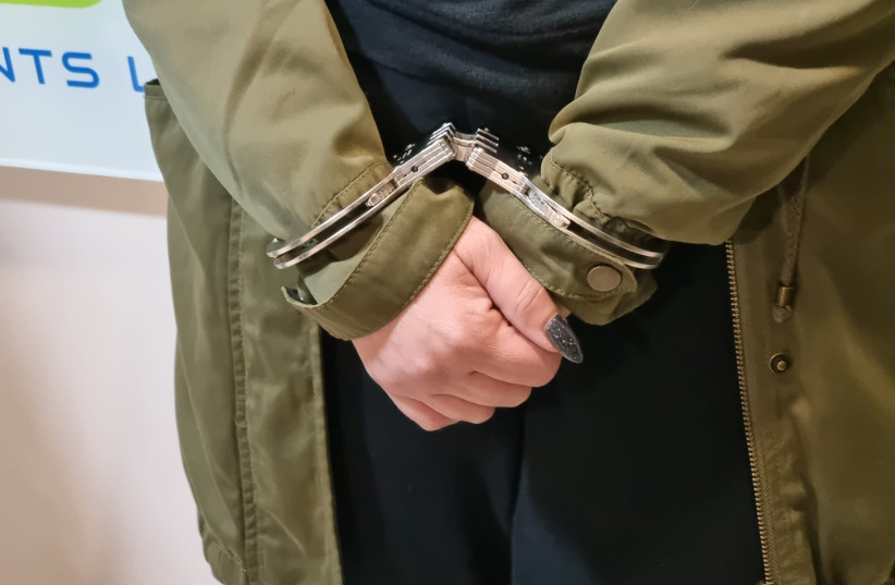  A suspect is seen in handcuffs, arrested after an Israel Police raid on a crime ring that defrauded tens of millions from Israel's National Insurance, on February 28, 2023. (photo credit: POLICE SPOKESPERSON'S UNIT)