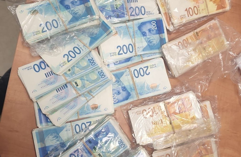  Piles of money are seen at the offices of a crime ring that allegedly defrauded tens of millions from Israel's National Insurance, on February 28, 2023. (credit: POLICE SPOKESPERSON'S UNIT)