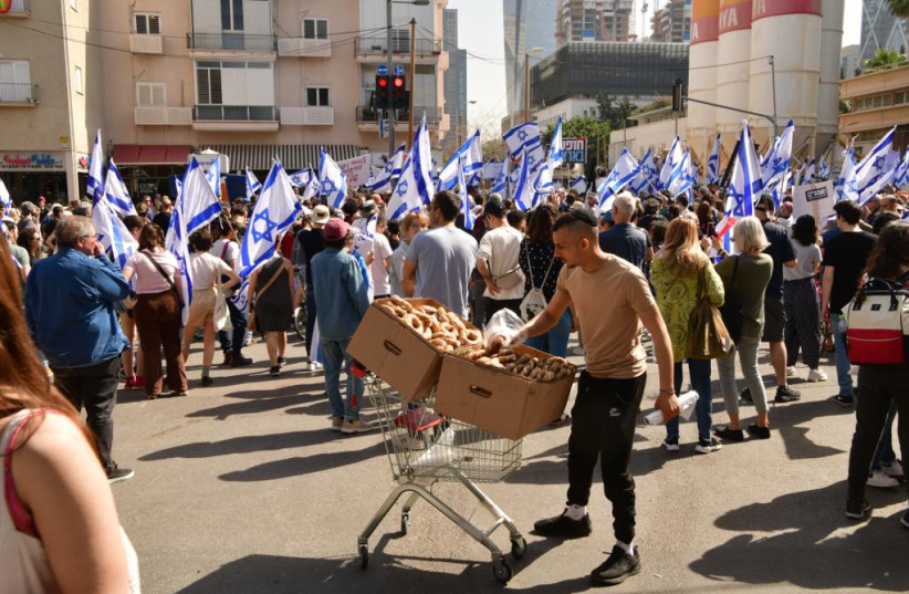  A street vendor sells bagels amid a crowd of protesters demonstrating against judicial reform in Tel Aviv, March 1, 2023. (credit: AVSHALOM SASSONI)
