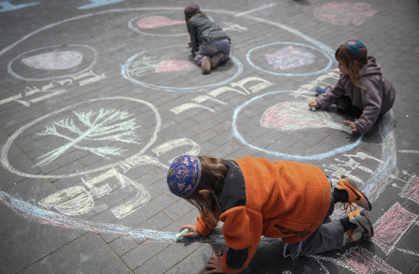  Religious Jewish family seen drawing with chalk on the pavement the Passover seder plate in central Jerusalem on March 31, 2015, ahead of the passover holiday starting on April 3 (credit: HADAS PARUSH/FLASH90)