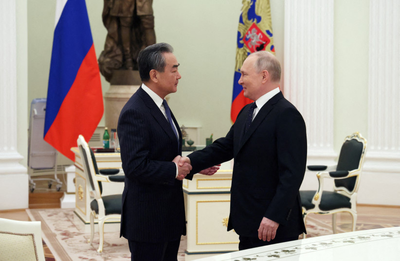   Russia's President Vladimir Putin shakes hands with China's Director of the Office of the Central Foreign Affairs Commission Wang Yi during a meeting in Moscow, Russia February 22, 2023.  (credit: Sputnik/Anton Novoderezhkin/Pool via REUTERS)