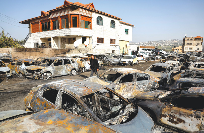  A RESIDENT OF Huwara walks on Monday among cars burnt by settlers avenging the terror attack that claimed the Yaniv brothers a day earlier.  (credit: AMMAR AWAD/REUTERS)
