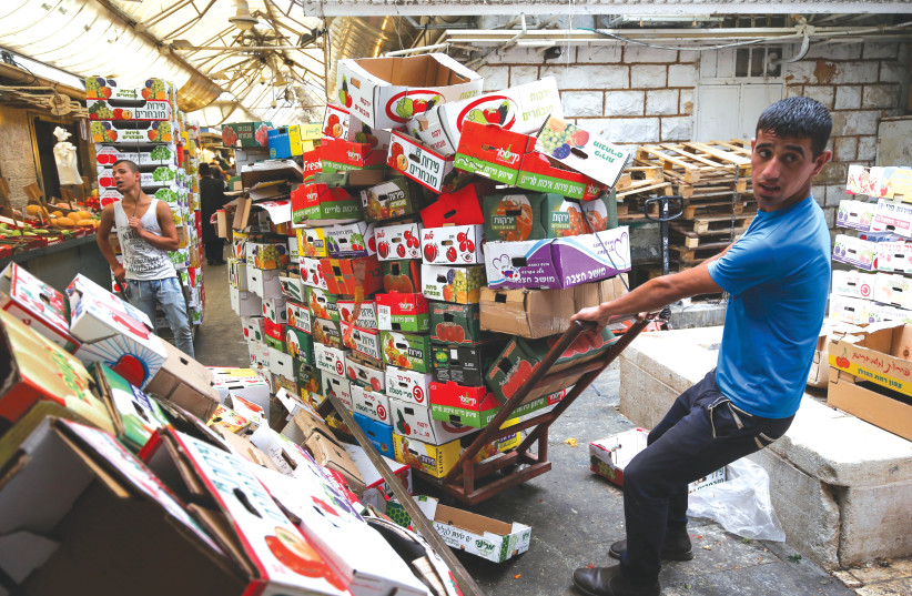  A WORKER gathers vegetable and fruit carton boxes at the Mahaneh Yehuda market in Jerusalem. (photo credit: NATI SHOHAT/FLASH90)