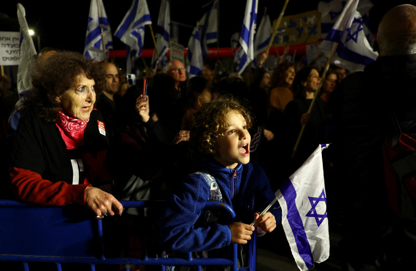  People hold Israeli flags during a demonstration as Israeli Prime Minister Benjamin Netanyahu's government presses on with its contentious judicial overhaul, in Jerusalem, March 4, 2023.  (credit: RONEN ZVULUN/REUTERS)