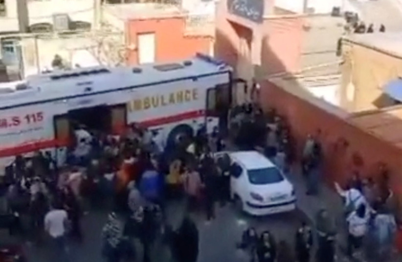  People gather around an ambulance outside a girls school after reports of poisoning in Fardis, Alborz province, Iran in this undated video still image released March 1, 2023 and obtained by REUTERS (photo credit: REUTERS)