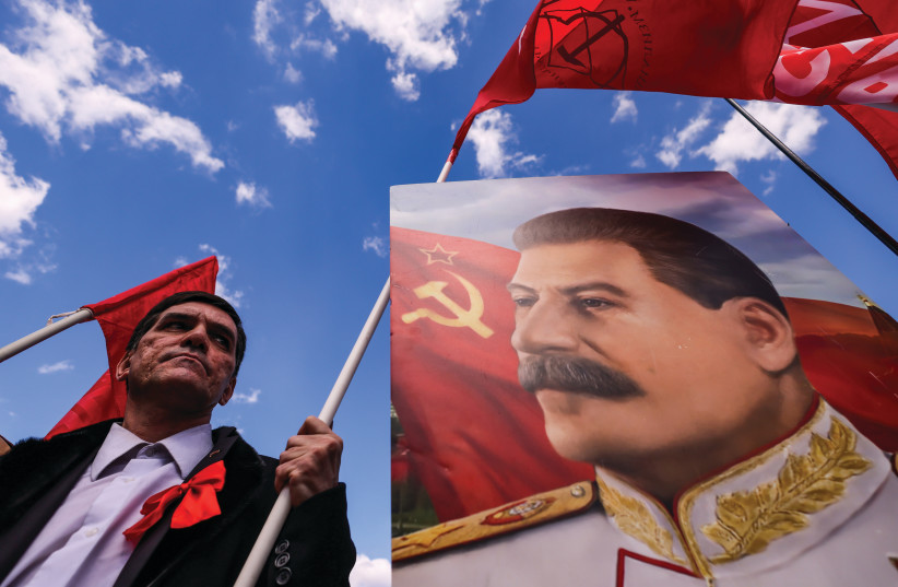  A SUPPORTER of the Russian Communist Party stands next to a portrait of Soviet leader Joseph Stalin, during a May Day rally in Moscow last year. (photo credit: MAXIM SHEMETOV/REUTERS)