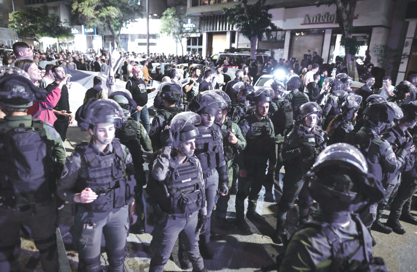  POLICE STAND guard as demonstrators protest against Sara Netanyahu near a hair salon in Tel Aviv, last Wednesday.  (photo credit: AVSHALOM SASSONI/FLASH90)