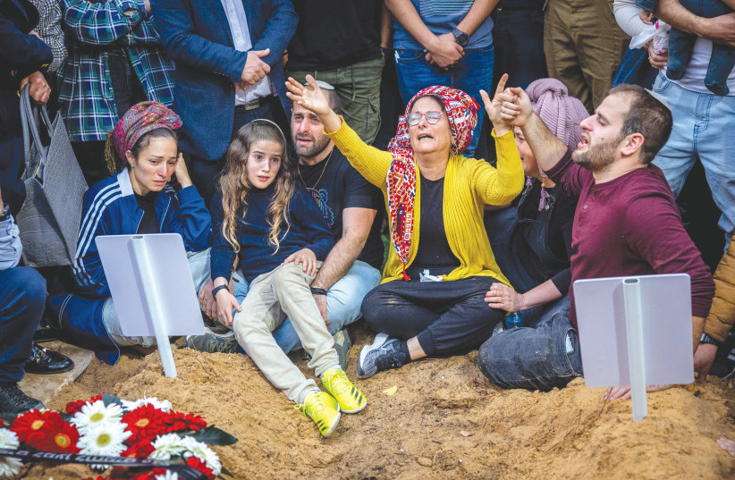  Mourners sit at the graves of brothers Hallel and Yagel Yaniv, who were ambushed in Huwara, at Mount Herzl military cemetery in Jerusalem last month.  (credit: YONATAN SINDEL/FLASH90)
