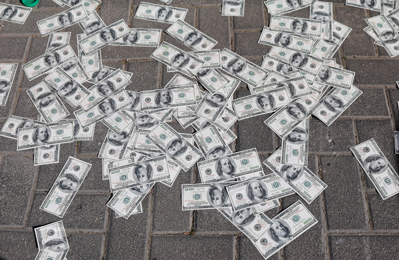 Fake dollar bills lie on the ground in Jerusalem on March 9, 2023 as Israelis demonstrate during ''Day of Resistance'' outside the headquarters of the Kohelet Policy Forum, a think tank which supports judicial changes.  (credit: AMMAR AWAD/REUTERS)