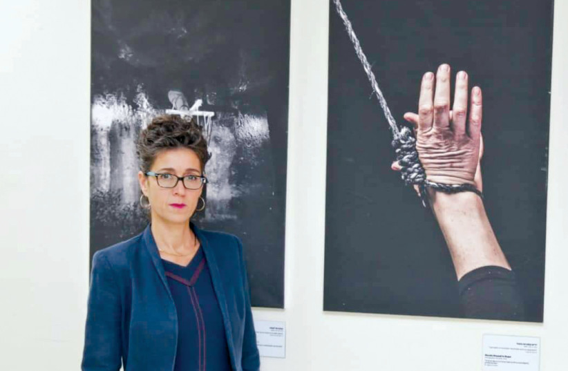  Pnina Omer, director of Ohr Torah Stone’s Yad La’isha, in front of an artistic photo exhibit on the pain of being in a trapped marriage. (photo credit: YONIT SCHILLER)