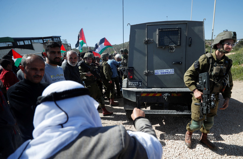  Israeli forces stand guard near their vehicle as Palestinians protest against a new Israeli settlement near Ramallah in the Israeli West Bank, March 10, 2023. (photo credit: MOHAMAD TOROKMAN/REUTERS)