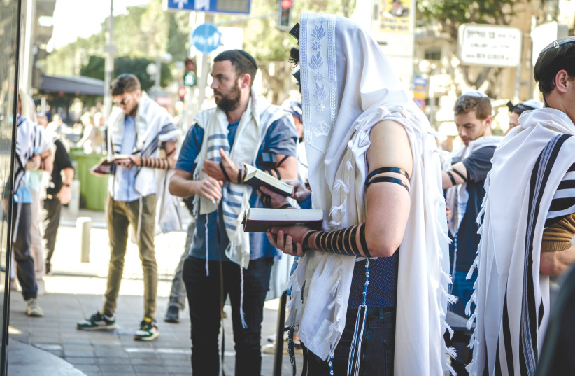  JEWS PRAY on Friday morning at the scene of the previous night’s terror attack on Dizengoff Street, in Tel Aviv. ‘Arab terrorists never try to kill only a certain type of Jew.’ (photo credit: AVSHALOM SASSONI/FLASH90)