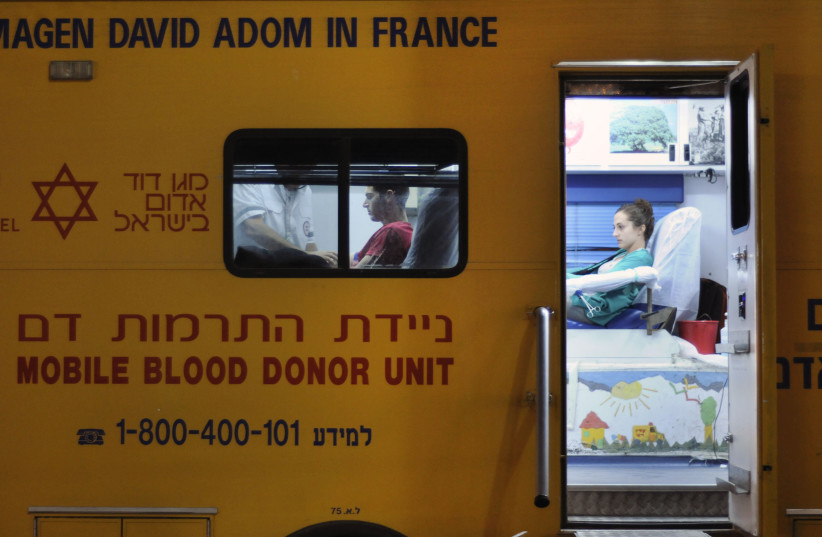  A person donates blood at a mobile blood donor unit operated by Magen David Adom. (credit: LOUIS FISHER/FLASH90)