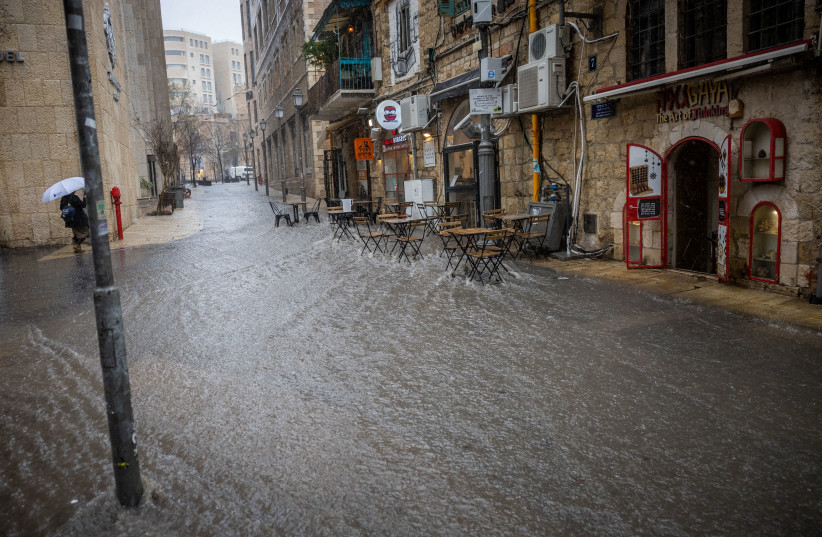  People seen during heavy rain in downtown Jerusalem, on March 14, 2023.  (credit: YONATAN SINDEL/FLASH90)