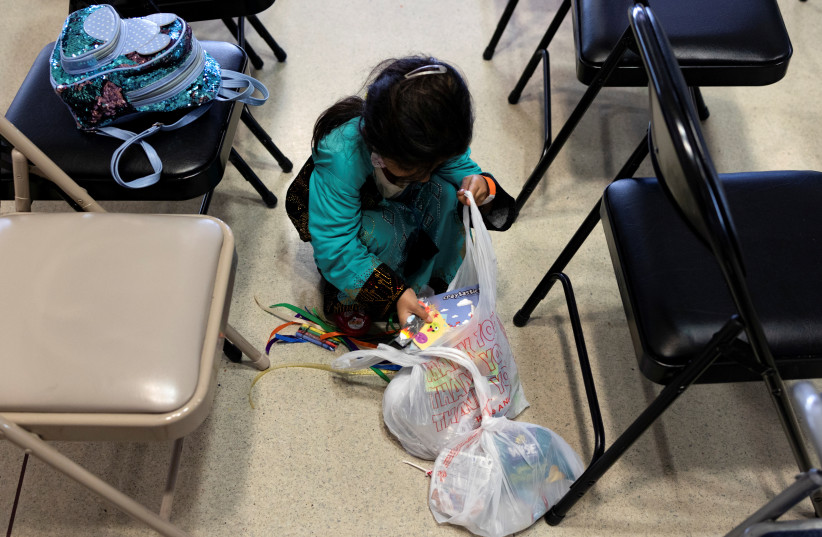  An Afghan evacuee child packs the items she received from participating in the social and emotional art initiatives run by Mural Arts after arriving at the Philadelphia International Airport in Philadelphia, Pennsylvania, U.S., October 24, 2021 (credit: REUTERS)