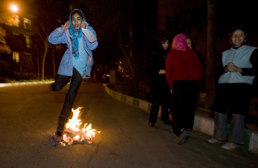  A girl jumps over a fire as she adjusts her headscarf during the Chaharshanbeh Soori festival in Tehran March 17, 2009. People jump over fires during the festival to burn away the year's sins on the last Tuesday night before the new year. (credit: REUTERS/RAHEB HOMAVANDI)