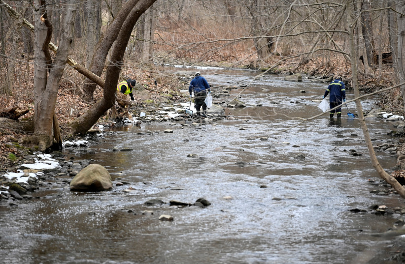 An environmental company is removing dead fish downstream from the site of the train derailment that forced people to be evacuated from their homes in East Palestine, Ohio, U.S., February 6, 2023 (photo credit: ALAN FREED/REUTERS)
