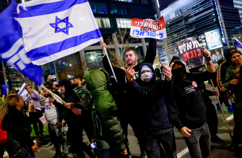  Judicial reform supporters wave Likud flags and hold signs reading ''The leftist minority will not determine Israel'' and ''Leftist traitors'' at a protest on Saturday night, March 18, 2023. (credit: ERIK MARMOR/FLASH90)