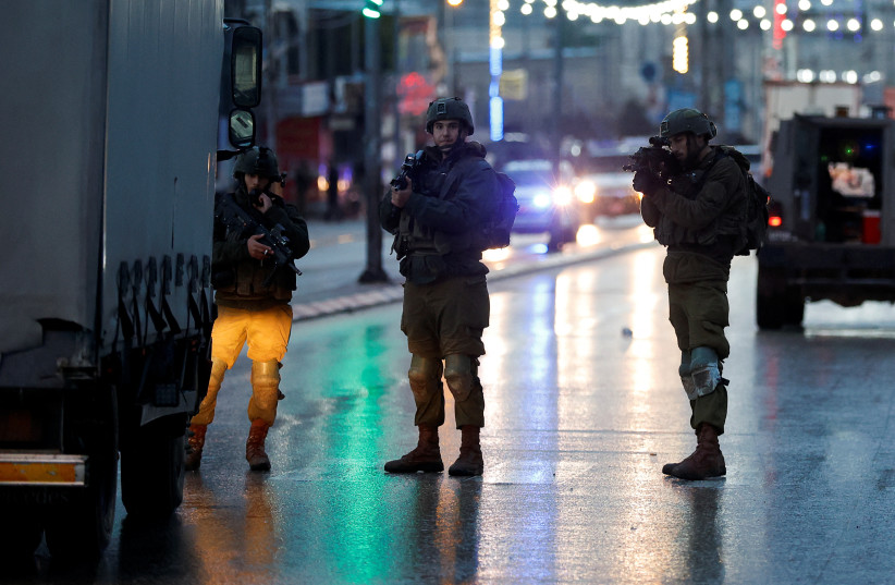  Israeli troops stand guard at a shooting scene, in Huwara, in the West Bank, March 19, 2023. (photo credit: MOHAMAD TOROKMAN/REUTERS)