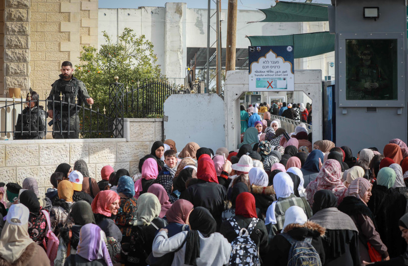  Palestinians make their way through an Israeli checkpoint to attend the first Friday prayers of Ramadan in Jerusalem's Al-Aqsa mosque, in Bethlehem in the West Bank March 24, 2023.  (credit: WISAM HASHLAMOUN/FLASH90)