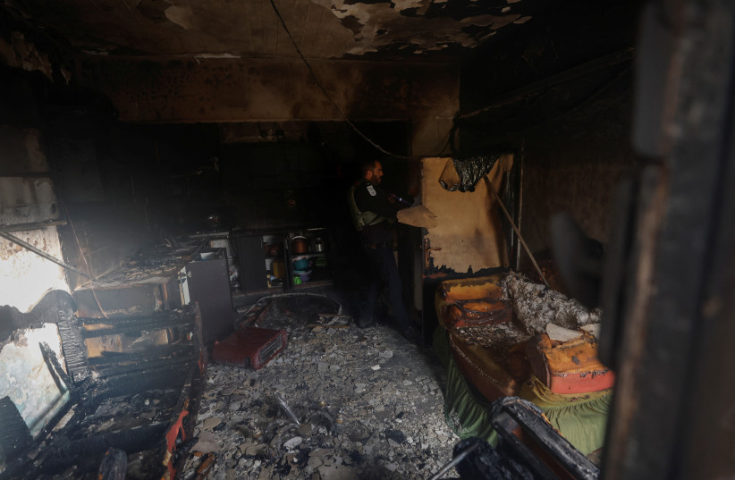  An Israeli policeman checks the damage in a Palestinian house which Palestinians say was attacked by Israeli settlers near Ramallah, in the West Bank, March 26, 2023 (credit: REUTERS/MOHAMAD TOROKMAN)
