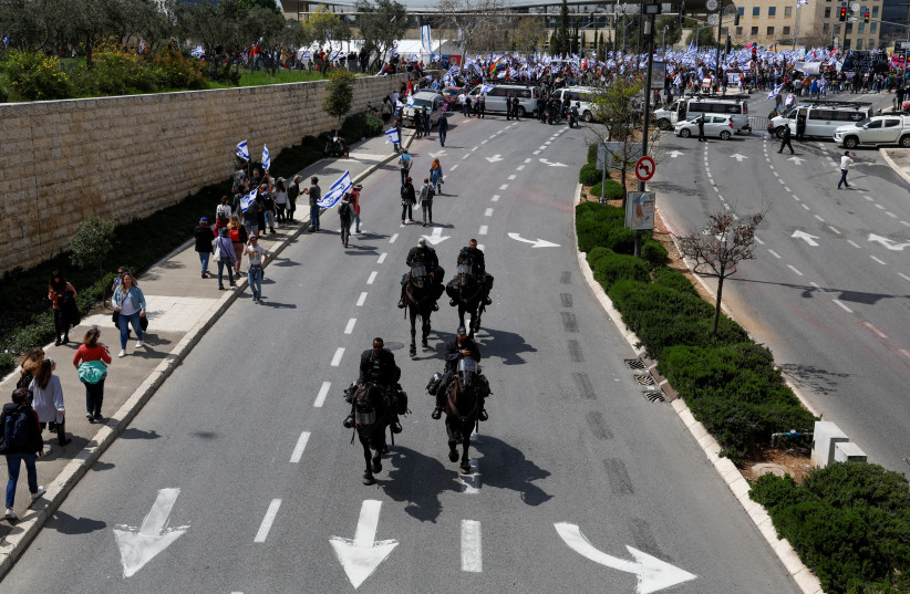  Mounted police officers ride on a road as people attend a demonstration after Prime Minister Benjamin Netanyahu dismissed the defense minister as his government presses on with its judicial overhaul, in Jerusalem, March 27, 2023 (credit: REUTERS/AMMAR AWAD)