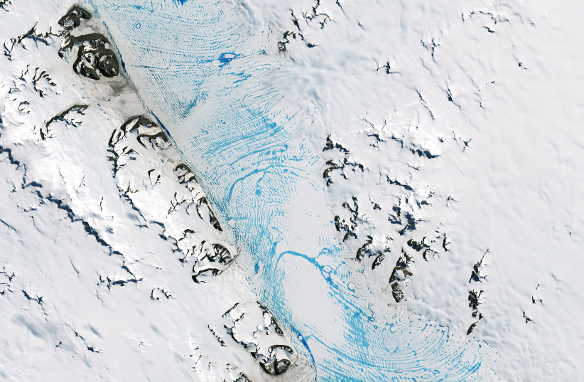  Blue meltwater spans an area of about 90 miles (140 kilometers) on the George VI ice shelf in Antarctica, January 19, 2020. (credit: NASA Earth Observatory/Lauren Dauphin/Handout via REUTERS )