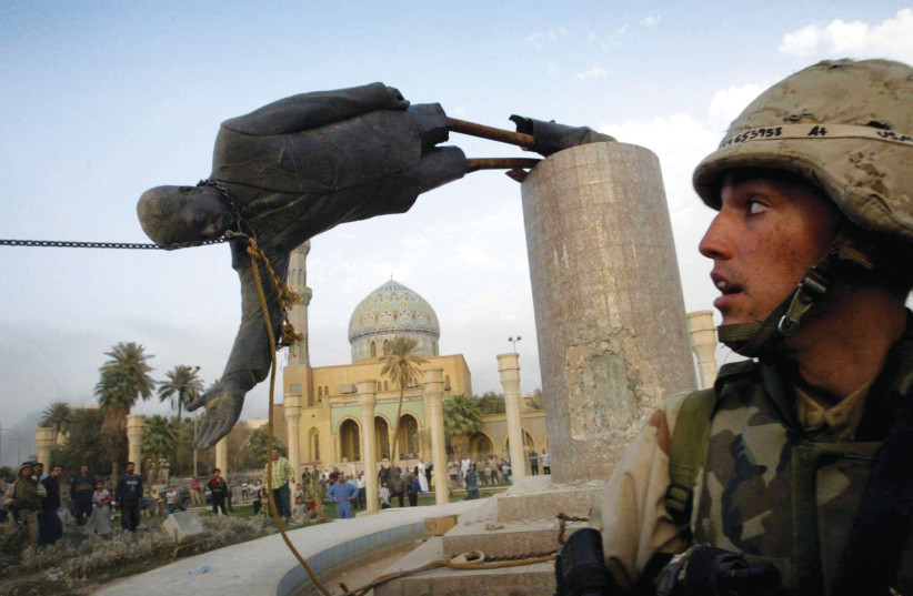  A US marine watches as a statue of Iraq’s president Saddam Hussein falls in central Baghdad’s Firdaus Square, 2003.  (credit: Goran Tomasevic/Reuters/File)