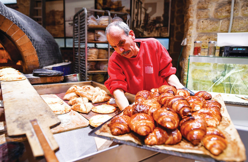  A BAKER presents fresh croissants – keep them away from hospitals during Passover.  (credit: AVSHALOM SASSONI/FLASH90)
