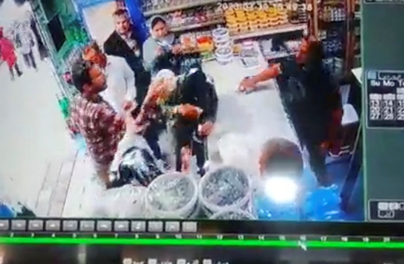  A screen grab of a handout video obtained from social media shows what appears to be a man throwing yogurt at two unveiled women in a shop near a holy Shi'ite Muslim city, Iran.  (credit: HANDOUT VIA WANA/VIA REUTERS)