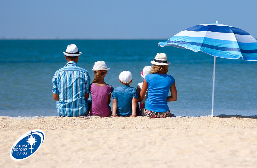  A family sits on the beach. (credit: ISRAEL CANCER ASSOCIATION)