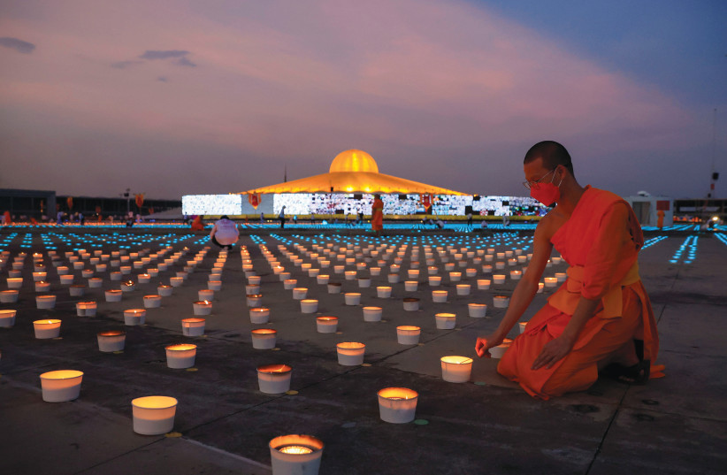  A BUDDHIST MONK lights candles during a ceremony to mark virtual Earth Day at Dhammakaya temple in Bangkok, last year. (credit: Soe Zeya Tun/Reuters)