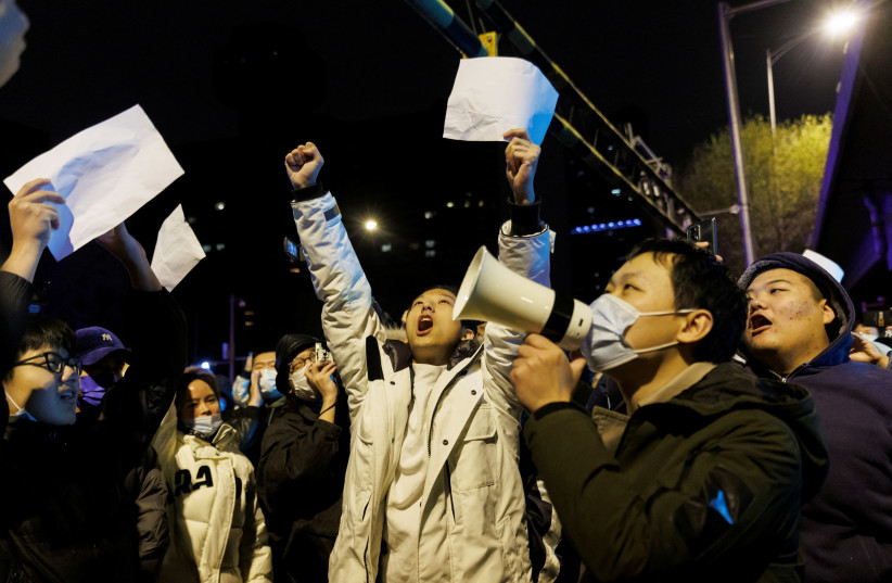 People shout slogans and hold up papers during a protest against coronavirus disease (COVID-19) restrictions after a vigil for the victims of a fire in Urumqi, as outbreaks of COVID-19 continue, in Beijing, China, November 28, 2022. (credit: THOMAS PETER/REUTERS)
