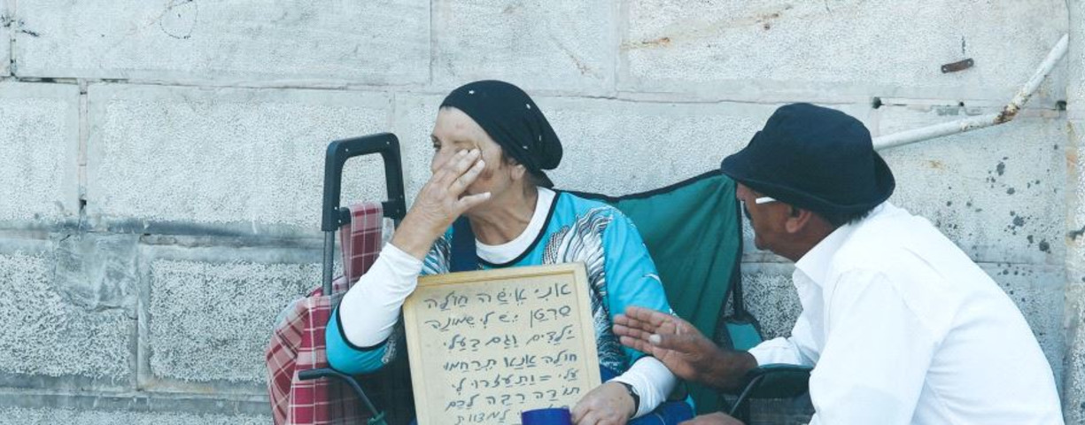 A PASSERBY stops to console a poor woman in Jerusalem in 2015.